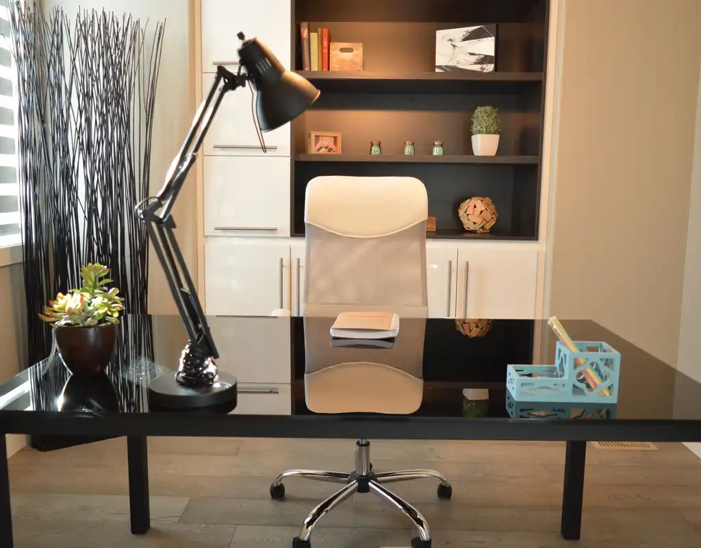 Black articulated desk lamp on glass office desk with ergonomic chair small home office