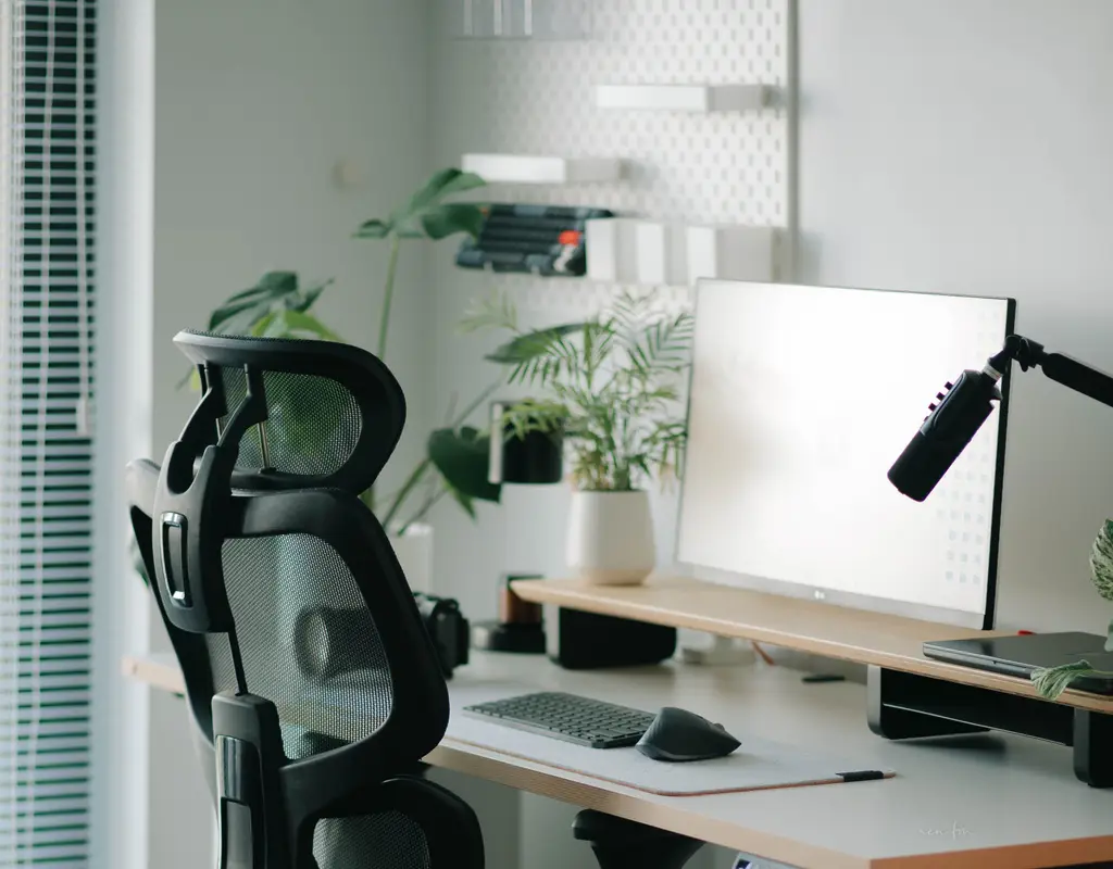 Black mesh office chair with adjustable headrest in a small home office