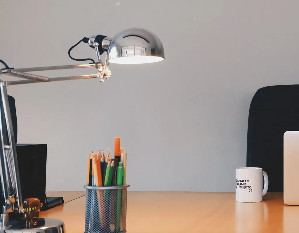 Chrome clamp-mount task lamp attached to a small wooden desk
