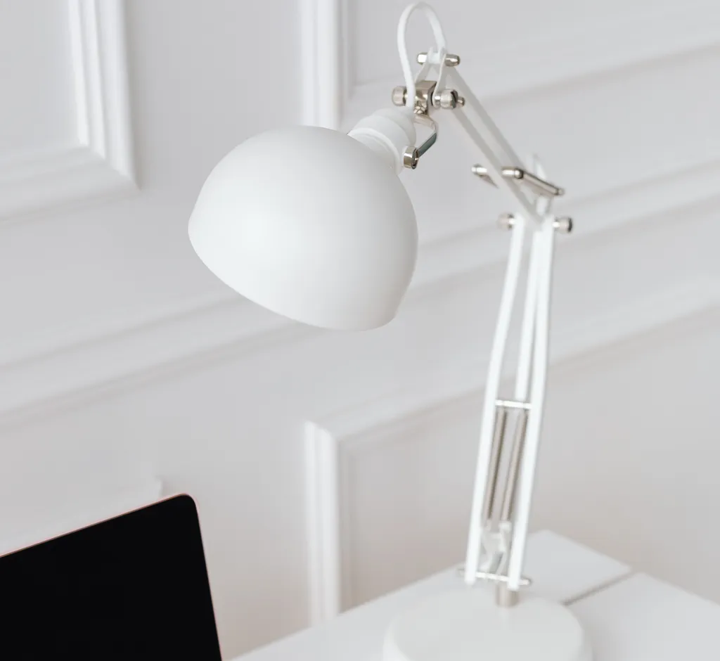 Adjustable white desk lamp beside a laptop on a clean white desk