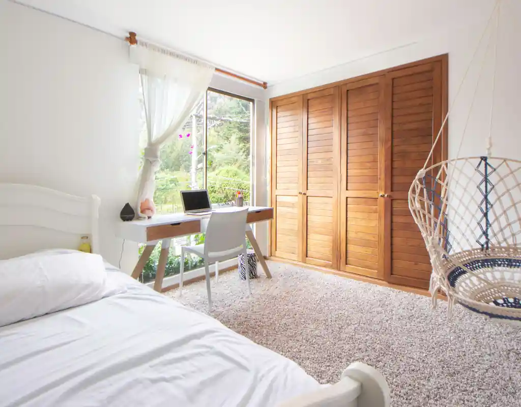 Small bedroom with desk and workspace area organized alongside the bed