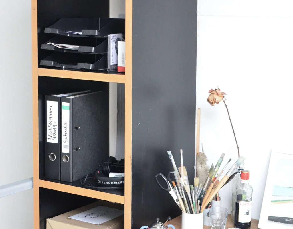 narrow vertical shelf beside a desk in a small home office