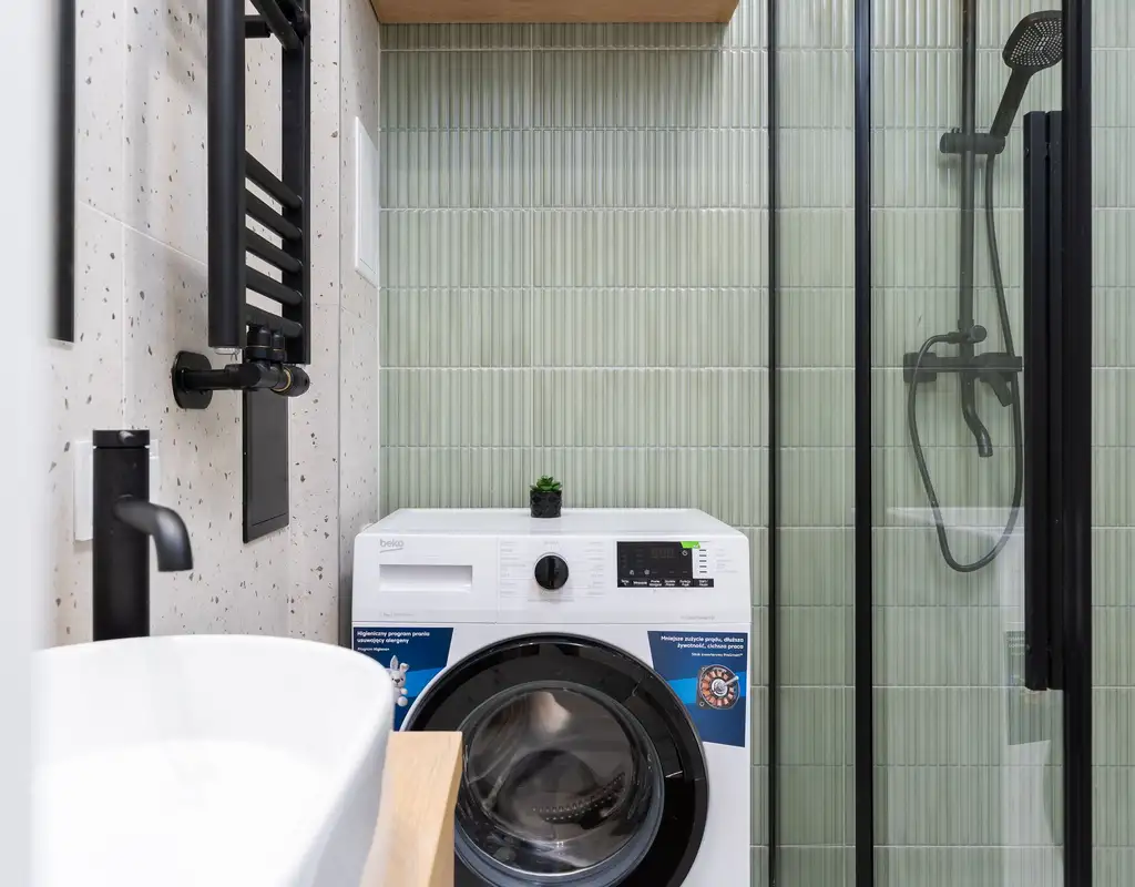 Small apartment laundry area with a compact drying rack, slim hamper, and organized laundry supplies