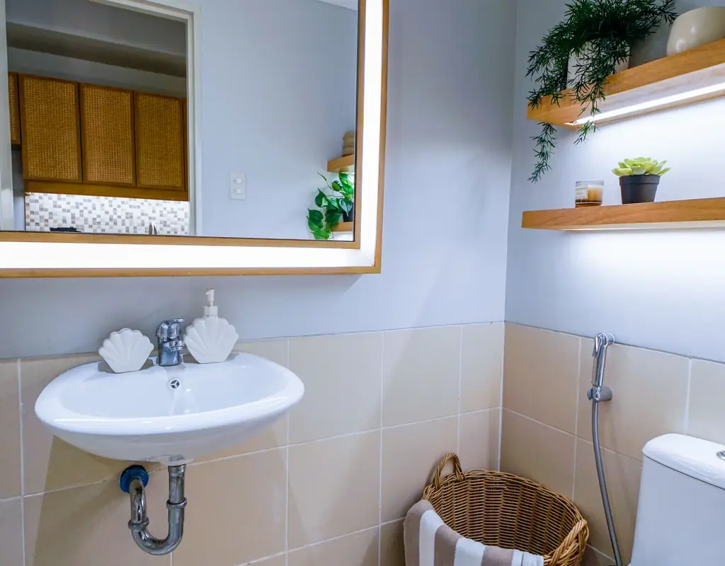 Small bathroom with light colors, large mirror, and space-saving storage