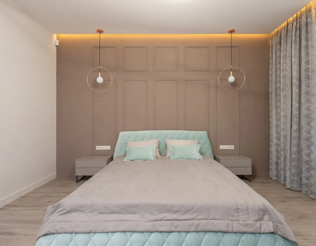 Bedroom with layered lighting — copper ring pendant lamps at bedside height and warm cove lighting along the ceiling edge